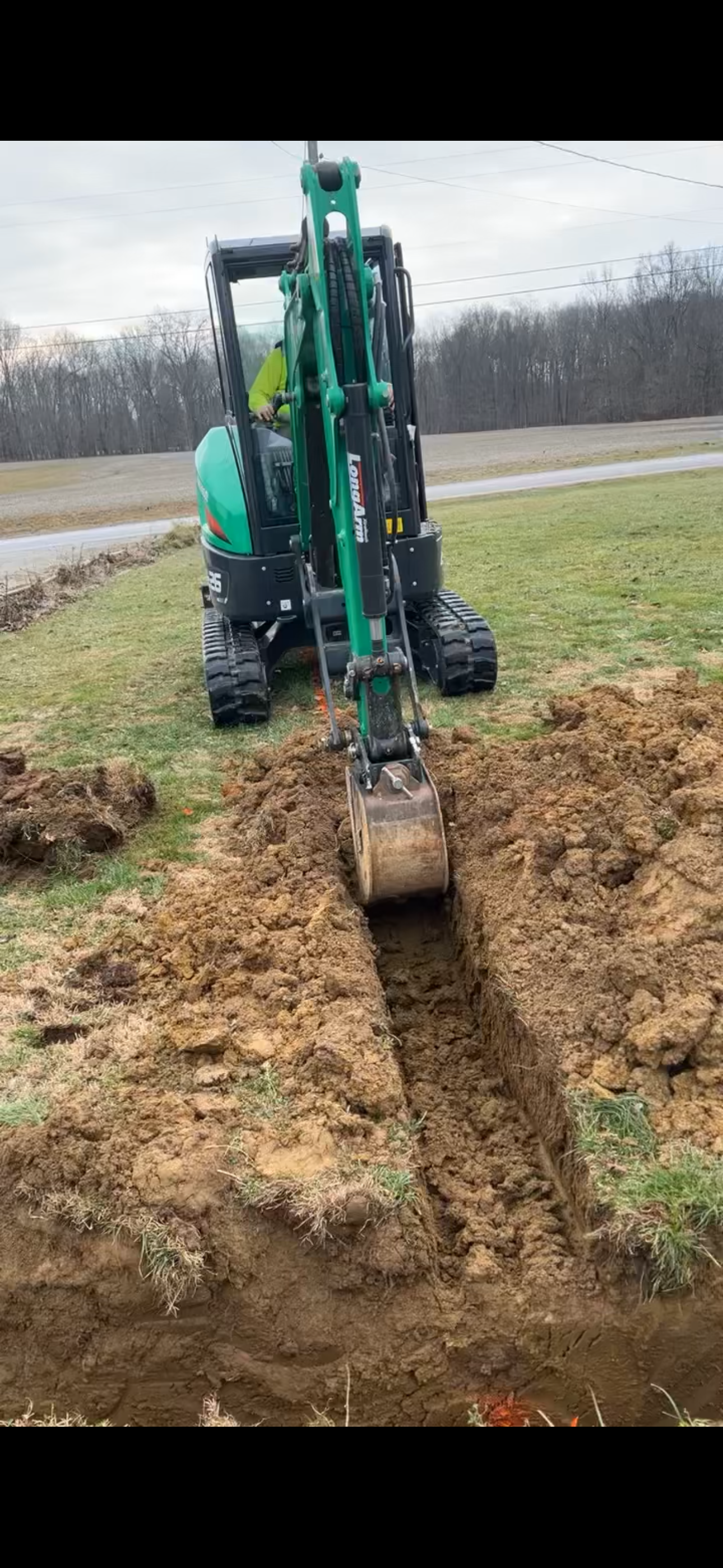 Excavator trenching for sewer repair at a residential property